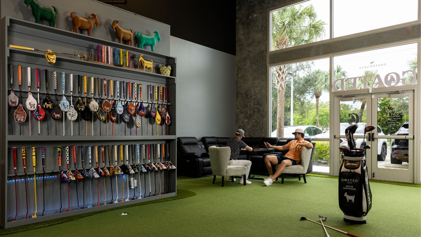 The GOATED Clubhouse lounge and putting green with a wall of GOATED putters